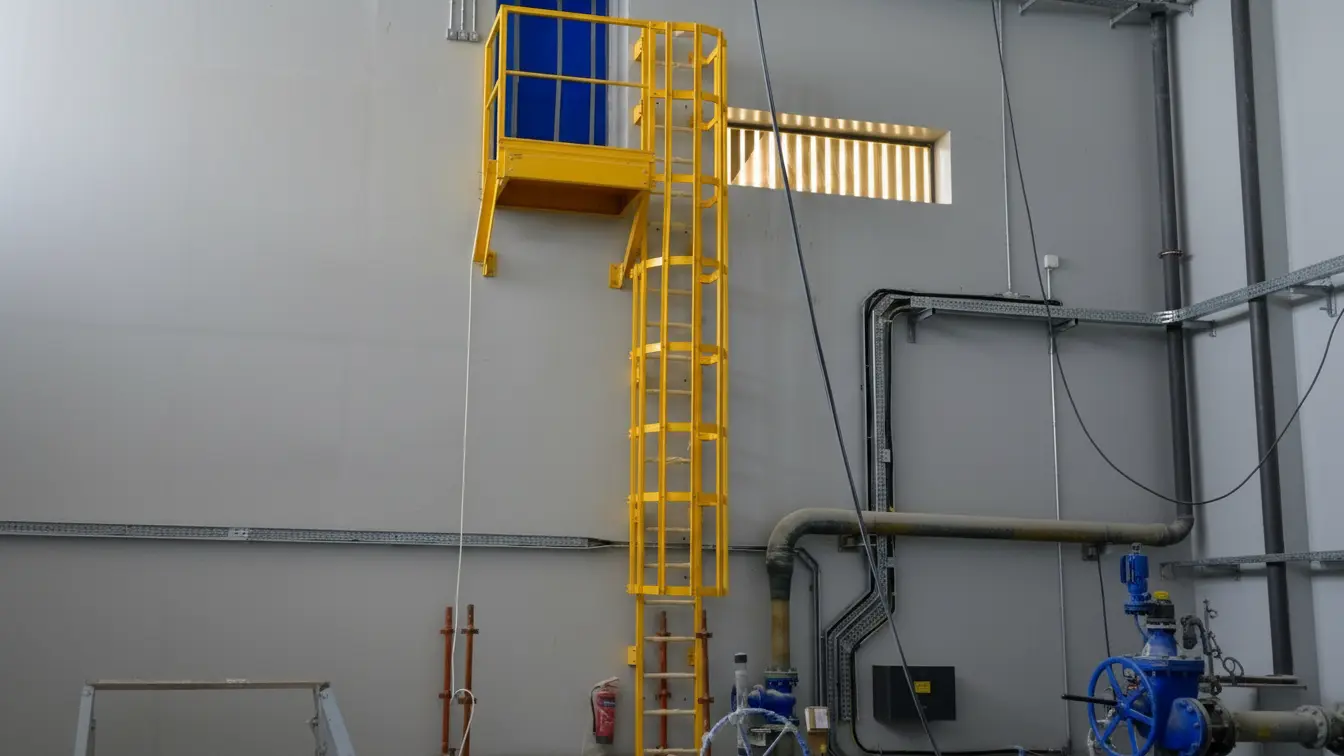 GRP ladder with safety cage installed in industrial facility for safe access